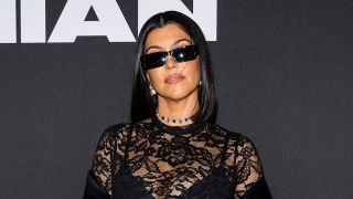 Kourtney Kardashian in all black sunglasses and body suit at a Boohoo event.
