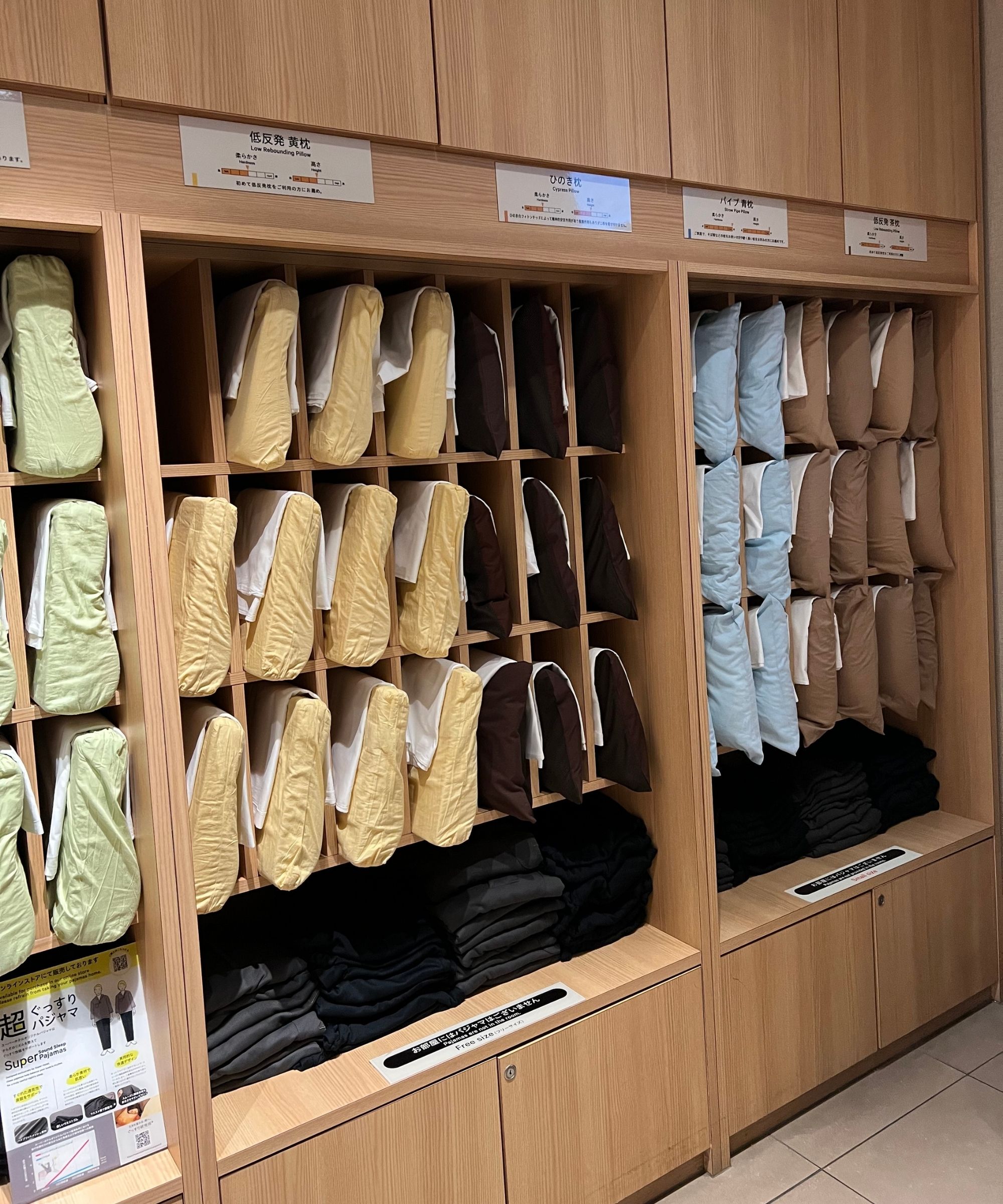 A wooden shelving unit filled with different pillows in different colored pillowcases.