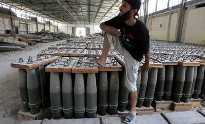 A rebel fighter and crates of shells in a Tripoli factory: Moammar Gadhafi's abandoned arsenal of missiles and chemical weapons could pose a big threat if it falls into the wrong hands.