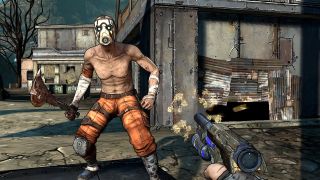 Screenshot from a Borderlands video game. You, the player, are pointing a gun at a shirtless man wearing orange trousers, a white facemask. He is wielding a large axe made from nails, a circular saw blade and other debris. In the background is a shanty town, with houses made out of corrugated metal sheets.