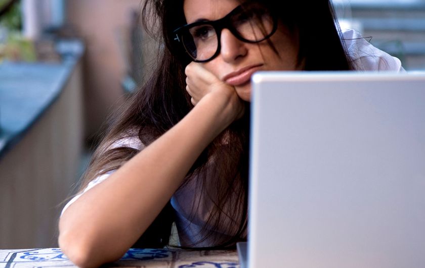 Woman looking upset in front of a laptop computer