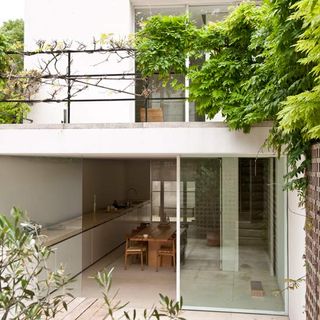 exterior of house with white walls trees and dinning table
