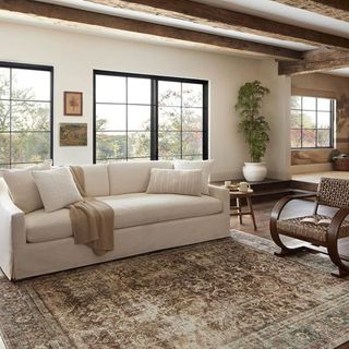 A farmhouse style living room with a white couch and patterned area rug