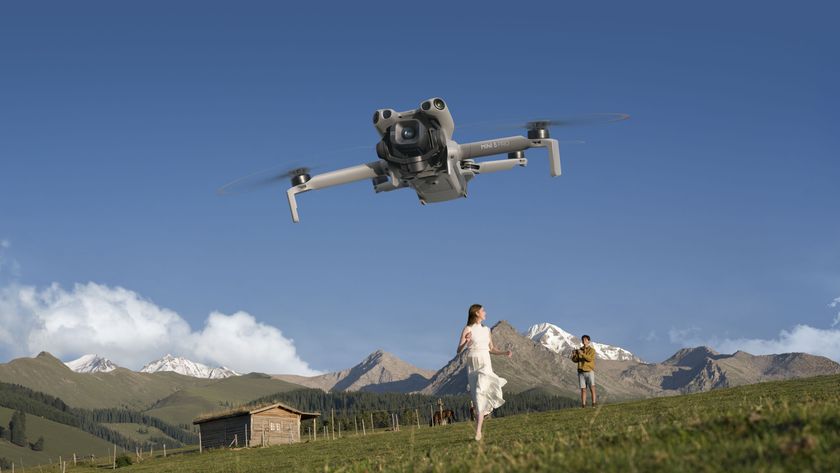 DJI Mini 5 Pro drone in flight on sunny day with mountain backdrop