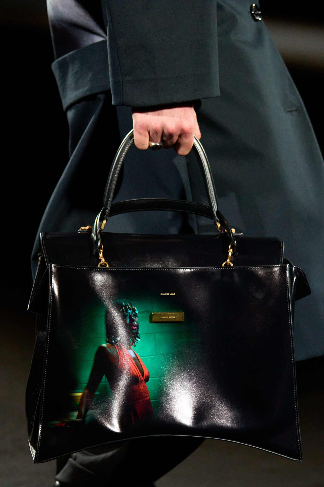 A close-up shot of a model walking in the Balenciaga F/W 26 show during Paris Fashion Week carrying a black handbag with Euphoria actress Danielle Deadwyler printed on it.
