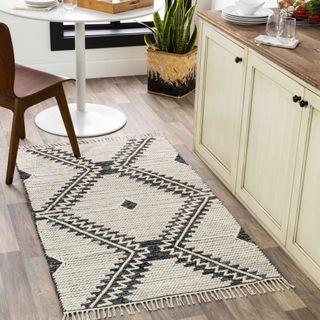 A cream rug with black diamond pattern next to a small dining room table