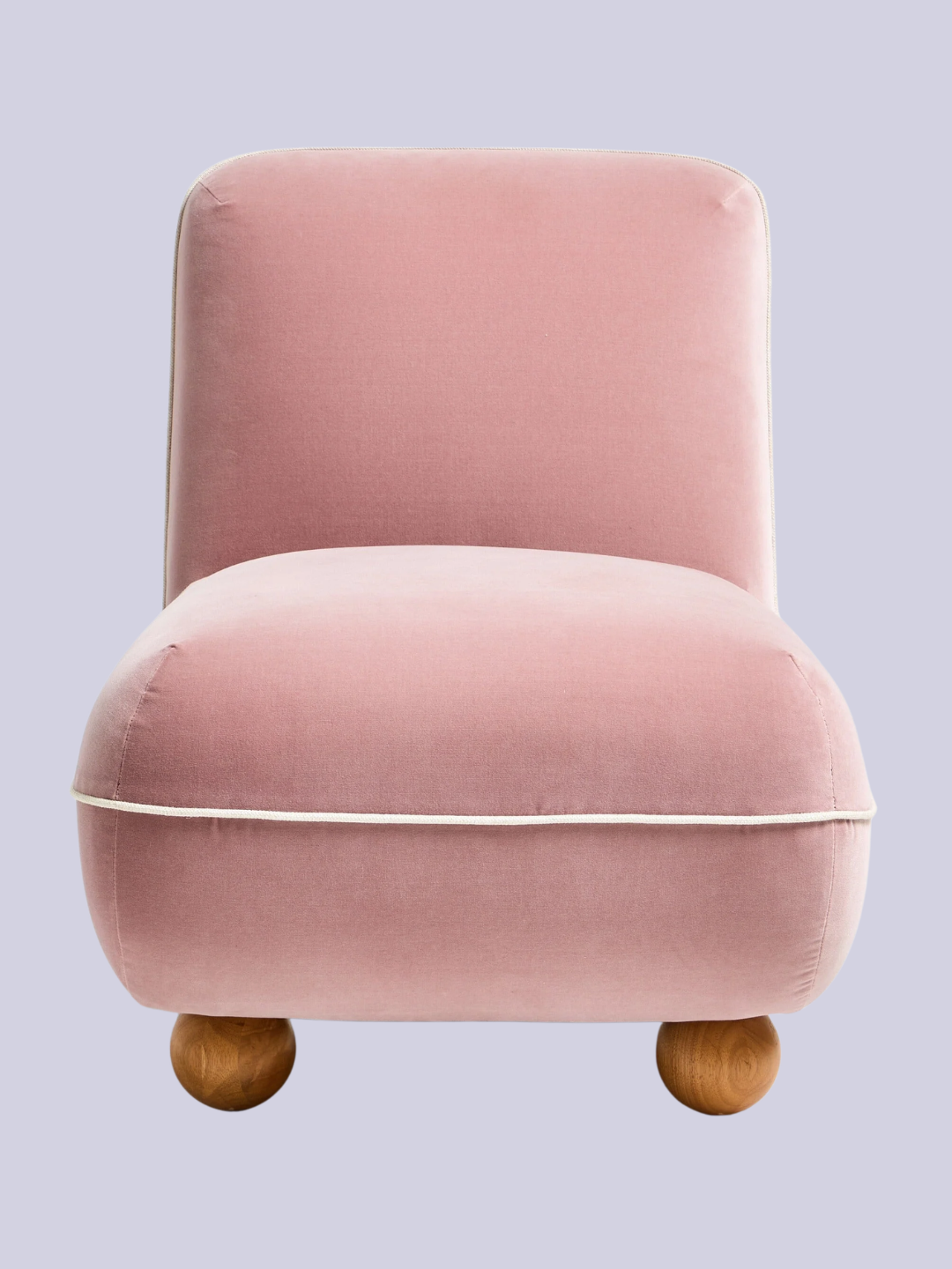 A blush pink sofa chair with wood bobbin feet