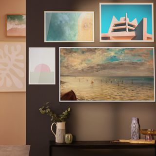 Samsung's The Frame TV hidden among art prints on a wooden wall