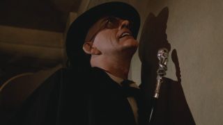 Christopher Lloyd examines a wall as he knocks it with his cane in Who Framed Roger Rabbit.