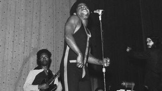 American soul singer and songwriter James Brown (1933-2006) performs live on stage with the J.B.'s, including guitarist Catfish Collins (1943-2010) behind, in East Ham, London in March 1971.