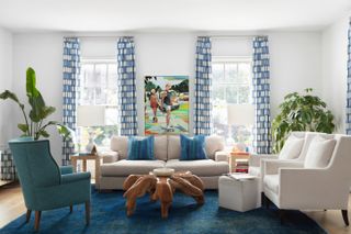 A blue and white living room with lots of natural green introduced