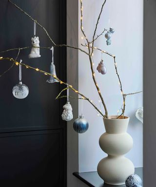 twigs in a vase with fariy lights and christmas baubles by John Lewis and Partners