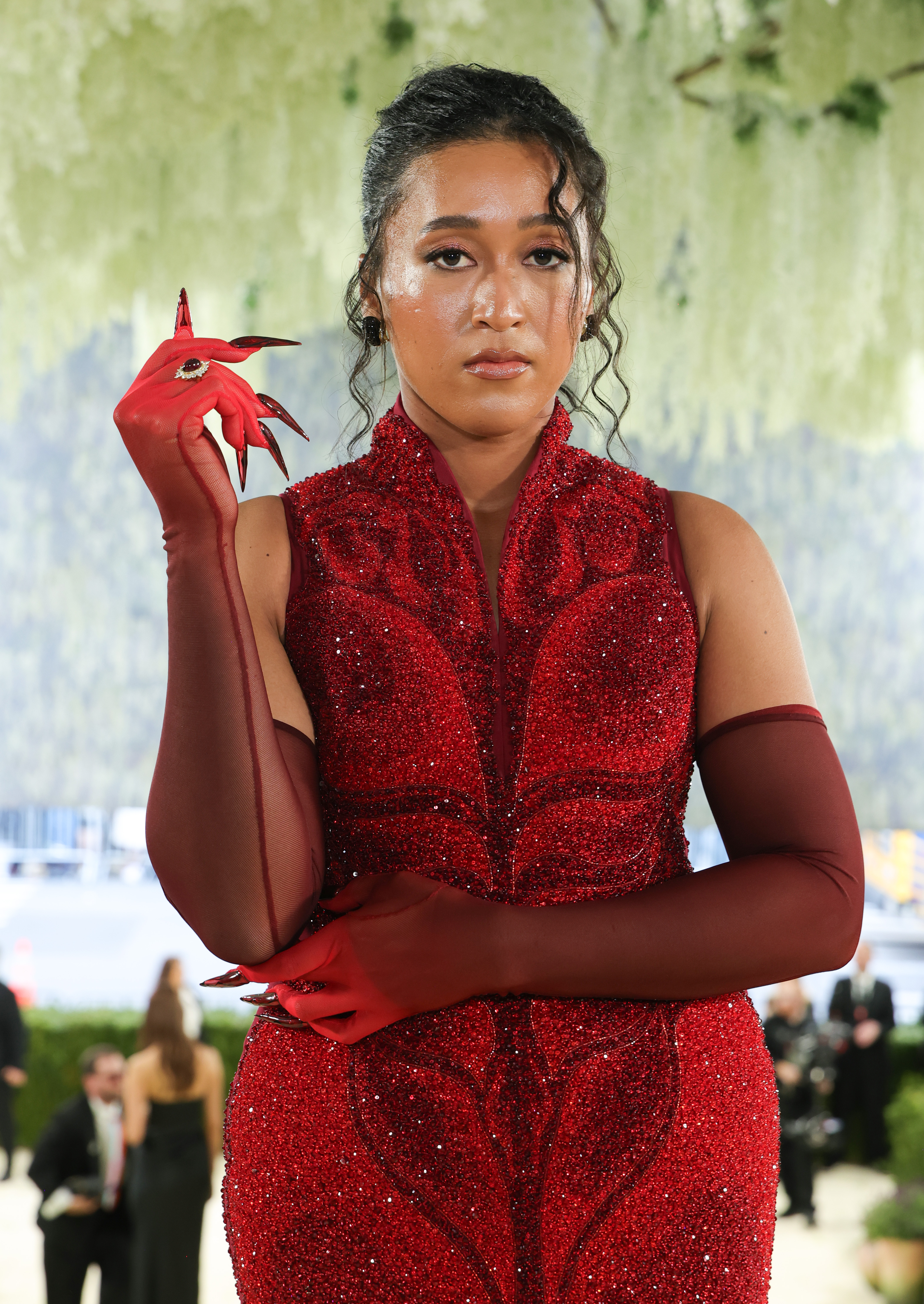 a woman with red gloves and claws in a red gown
