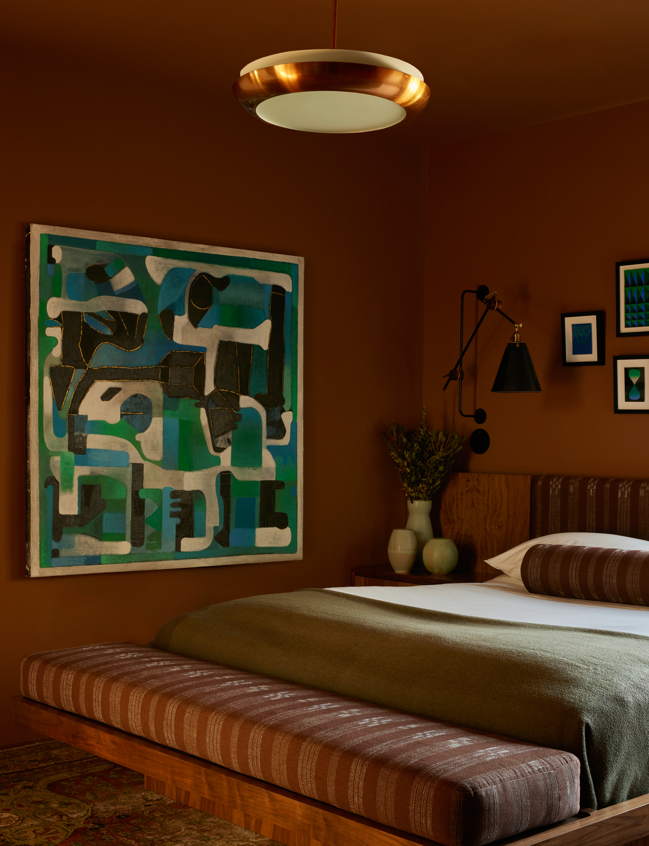 A bedroom drenched in deep tones of burgundy, with a low-to-floor bed in olive tones