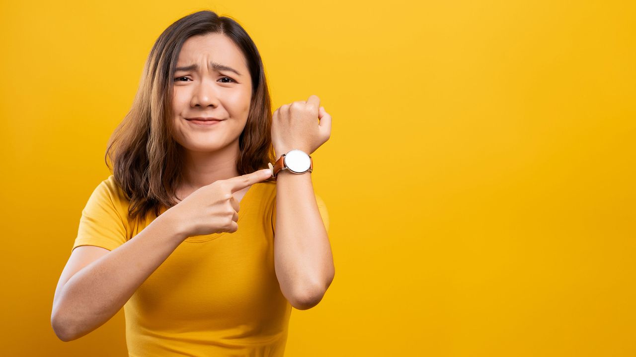 A stressed-out woman points at her watch.