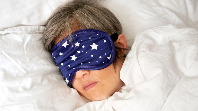 Woman asleep in bed wearing a sleep mask
