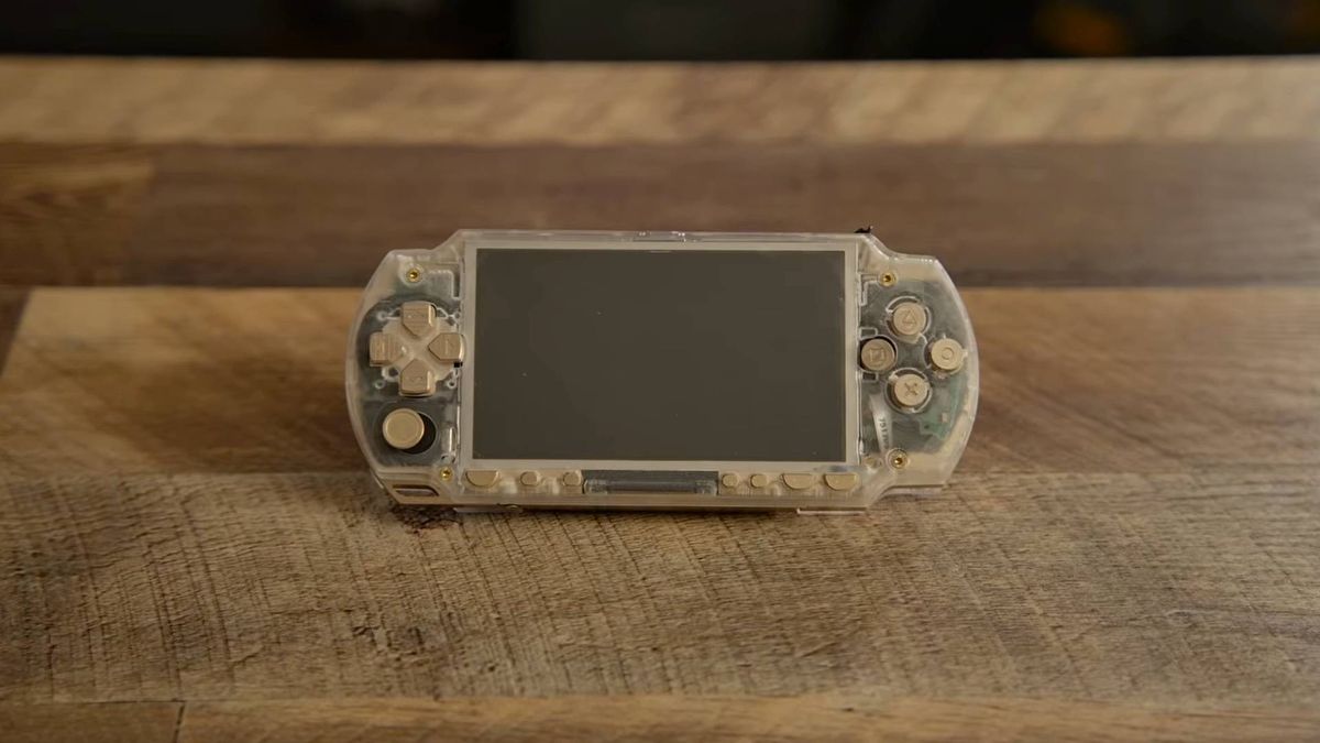 Brass and acrylic PSP sitting on woodgrain desk.