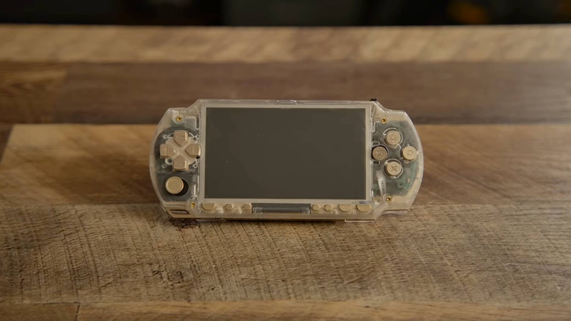 Brass and acrylic PSP sitting on woodgrain desk.