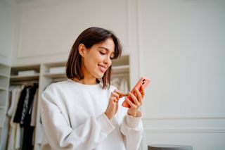 A woman using her phone while smiling.