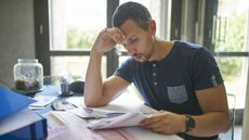 A man looks focused as he goes over paperwork at his desk at home.