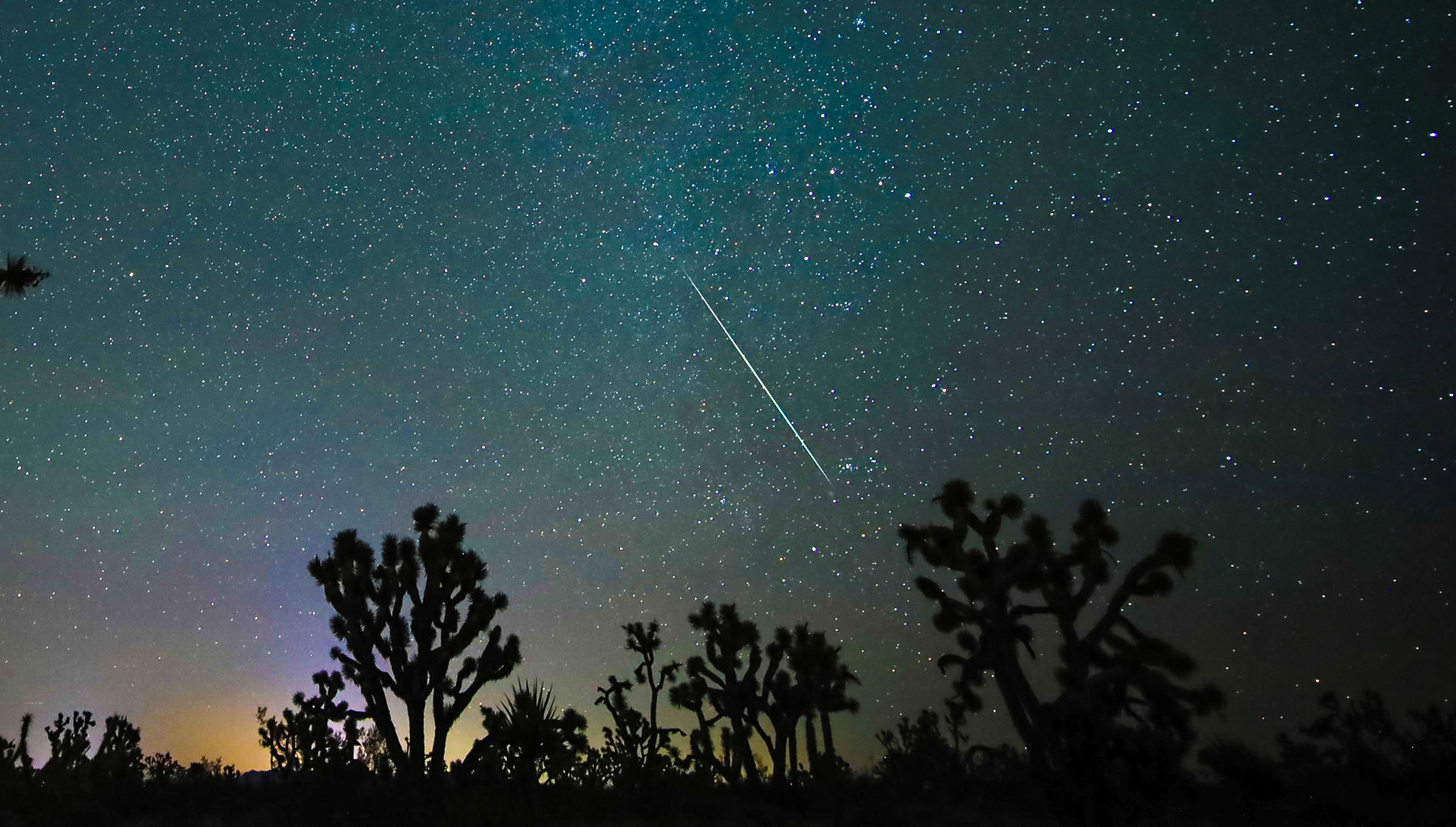 meteors streak through the starry night sky, leaving trails of light