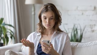 Confused woman looks at phone