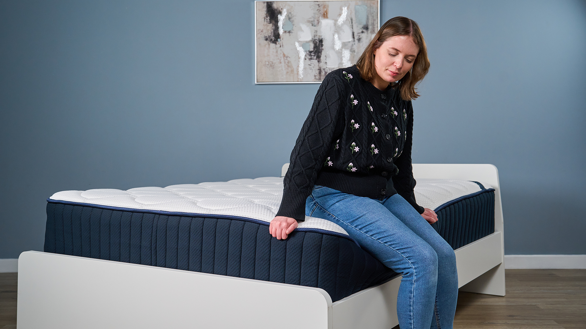 Mattress tester Ruth Jones sits carefully on the edge of a mattress, checking the support