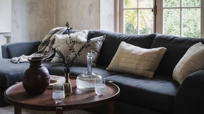 A dark navy slubby living room corner sofa with a wooden coffee table pulled close