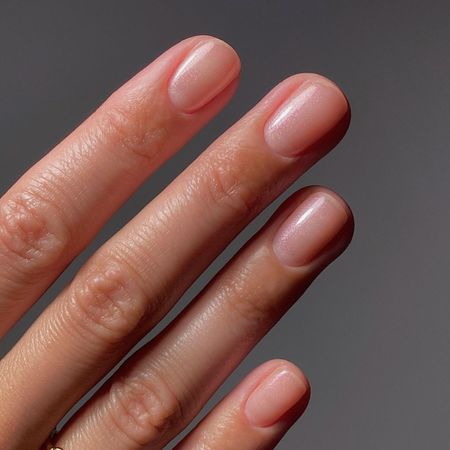 A close-up picture of a sheer, glossy manicure using a Manucurist nail polish