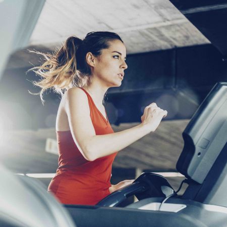 Woman in red vest running on treadmill