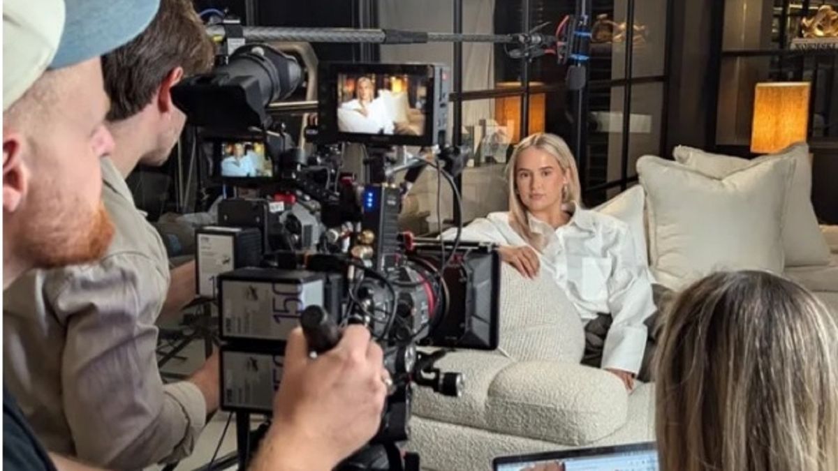 Molly-Mae Hague sitting on a white sofa as two men film her from behind a number of cameras for the docuseries Molly-Mae: Behind it All.