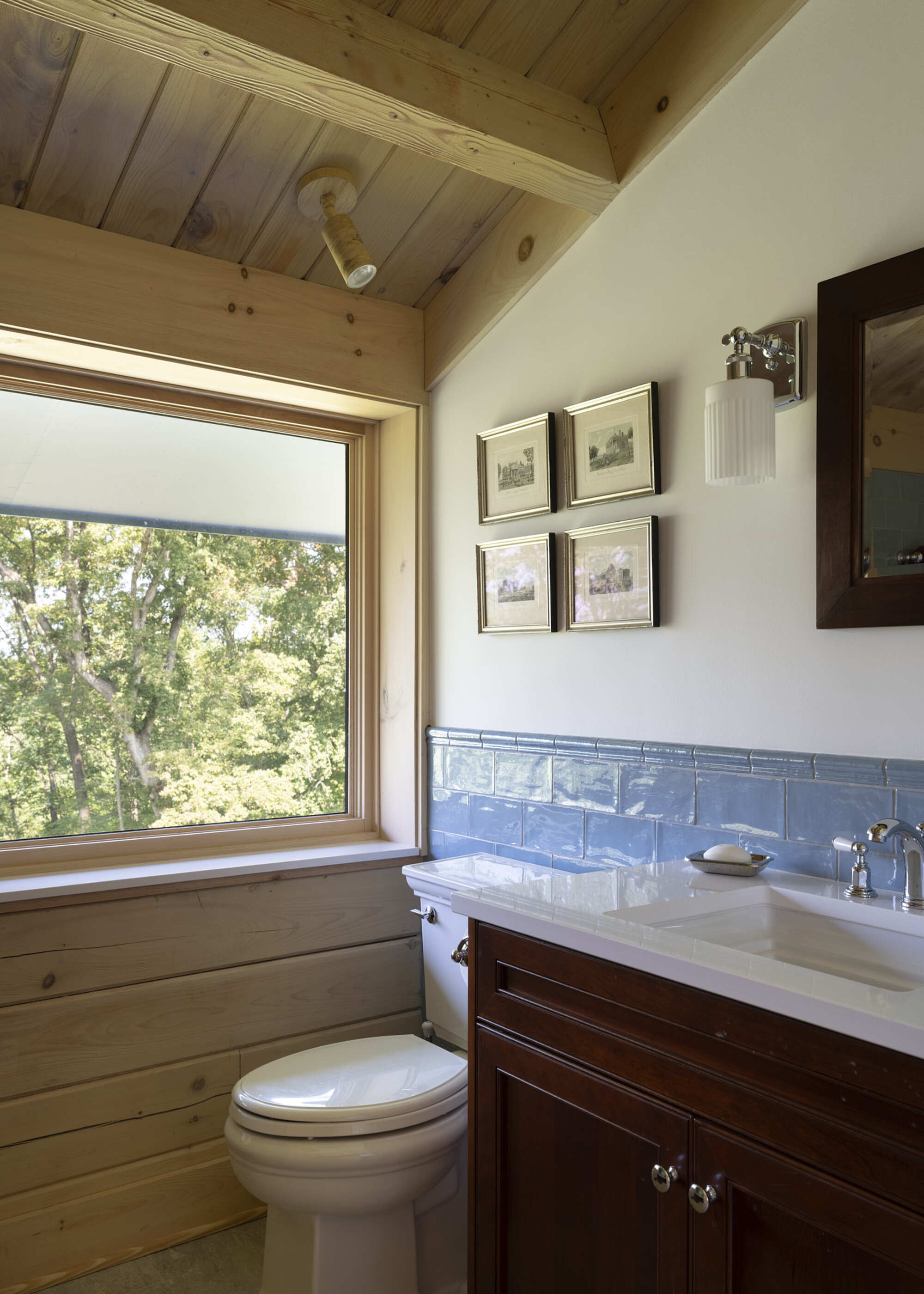 A small bathroom with a single vanity, wood clad walls, and a toilet in a small space