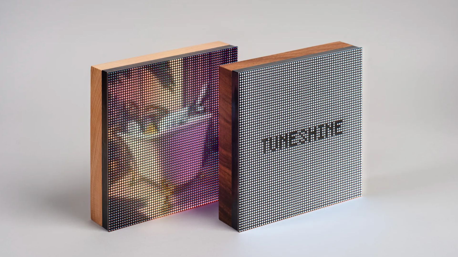 AN IMAGE OF TWO TUNESHINE SPEAKERS, ONE IS SHOWING AN ALBUM COVER, THE OTHER SHOWS THE SPEAKER WHEN NOTHING IS PLAYING ON IT, WHICH IS JUST SLATE GREY WITH 'TUNESHINE' WRITTEN ACROSS IT IN BLACK