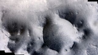 black and white image of mars from orbit showing polygonal features on a hilly landscape