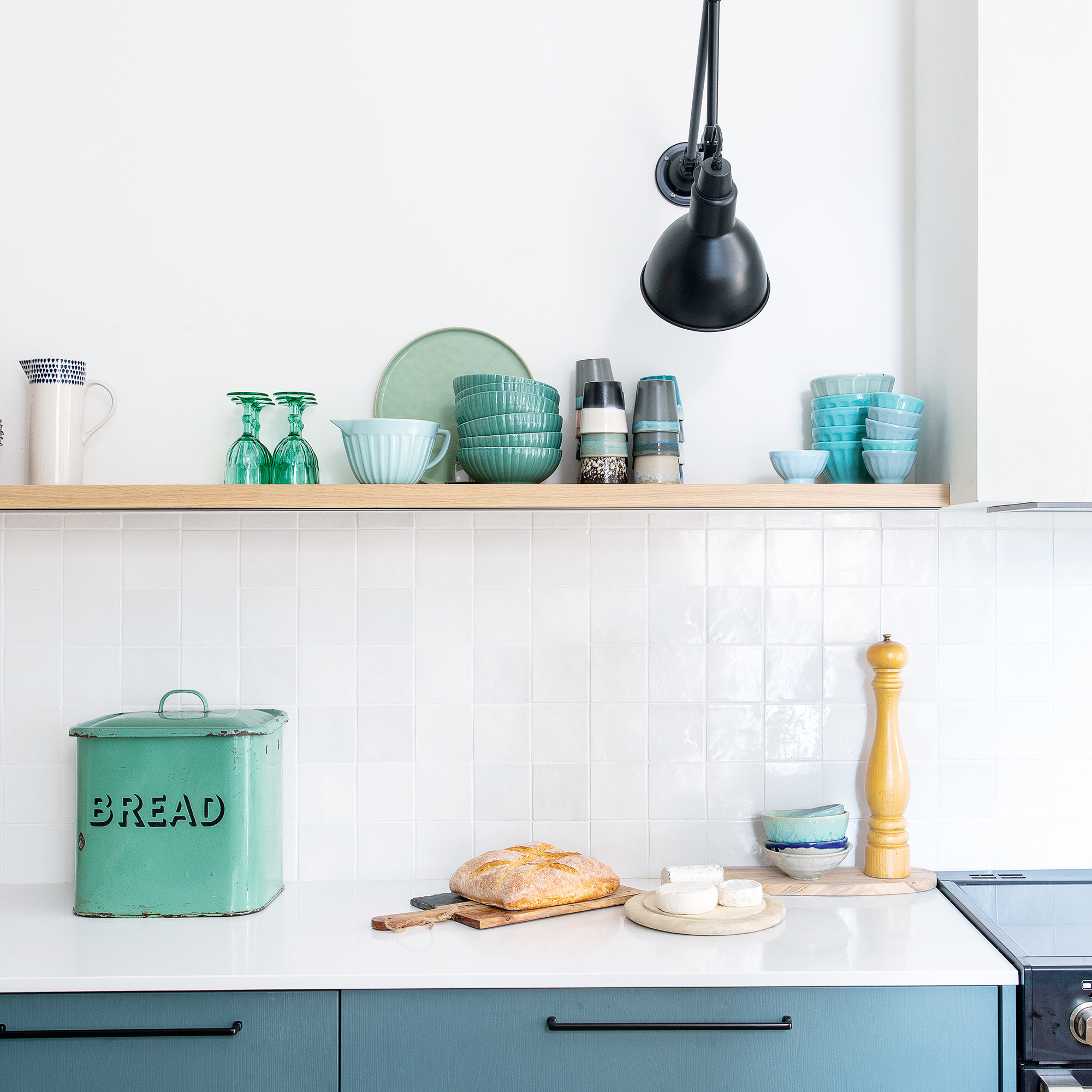 White kitchen with blue and green pieces on floating shelf