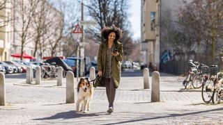 A woman walking her Collie dog through a city on a winter's day