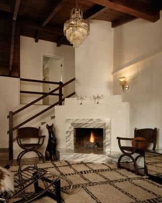 A living area with a modern fireplace with a marble fire surround, neutral rug, and two accent chairs