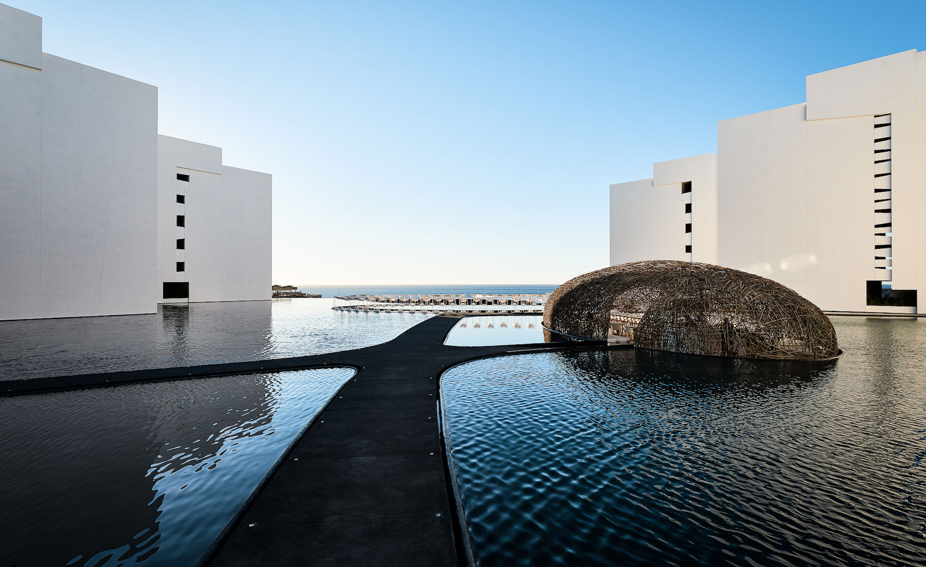 Water feature with enclosed architecturally designed structure with seating area inside