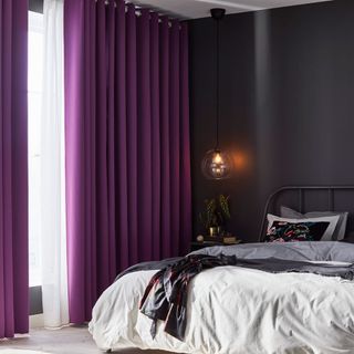 grey bedroom with purple curtains and white flooring