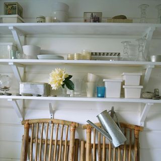 kitchen crockery wooden chair white walls and white flower on shelves