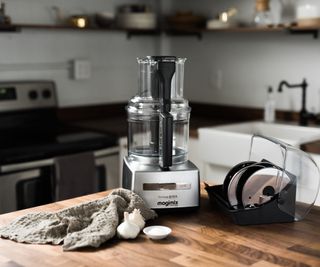 Magimix food processor on a wooden countertop with a wipe beside it