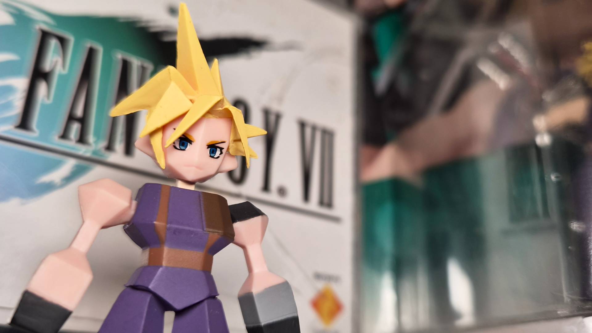 Photo of a Cloud Strife polygon toy sitting in front of the FF7 game box.
