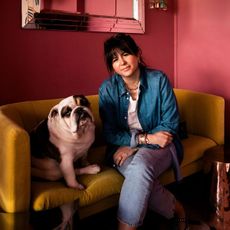 jewellery designer roxanne first and her dog sitting on a yellow sofa