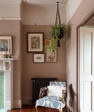 corner of living room showing cornicing, picture rail, edge of fireplace and cast iron radiator with armchair in front.