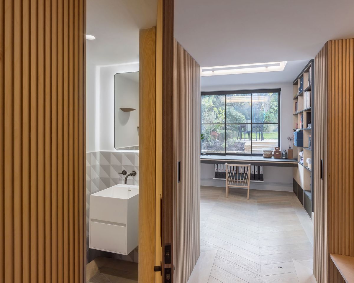 The same cladded hallway with the door to the doorstairs bathroom ajar