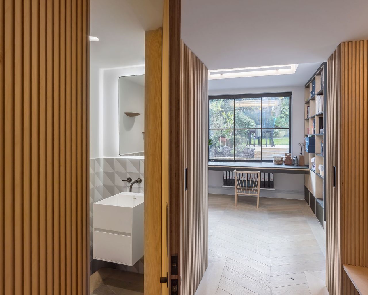 The same cladded hallway with the door to the doorstairs bathroom ajar
