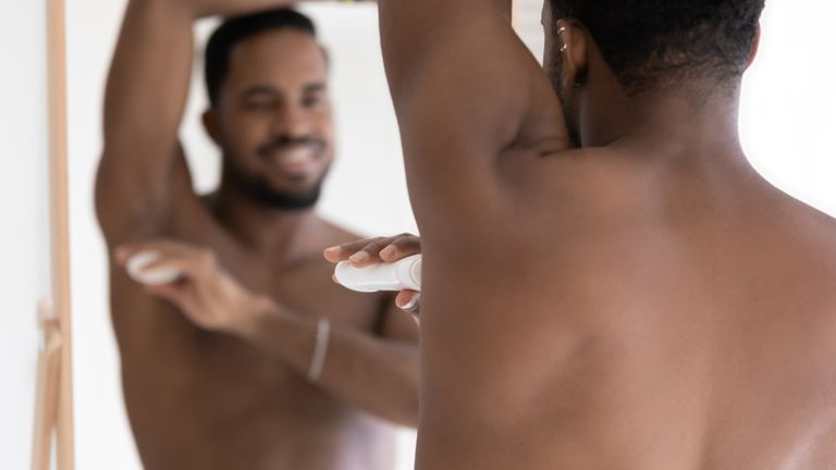 A man applying one of the best deodorants to his armpit – it's a roll on