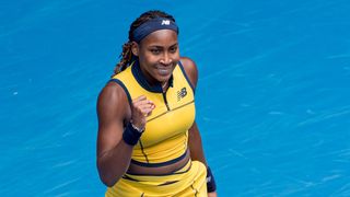 Coco Gauff, wearing a yellow New Balance tennis dress, clenches her fist on court ahead of the Kostyuk vs Gauff live stream at the Australian Open 2024