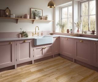 wood effect porcelain flooring in pink Shaker kitchen with brass cup handles and Belfast sink