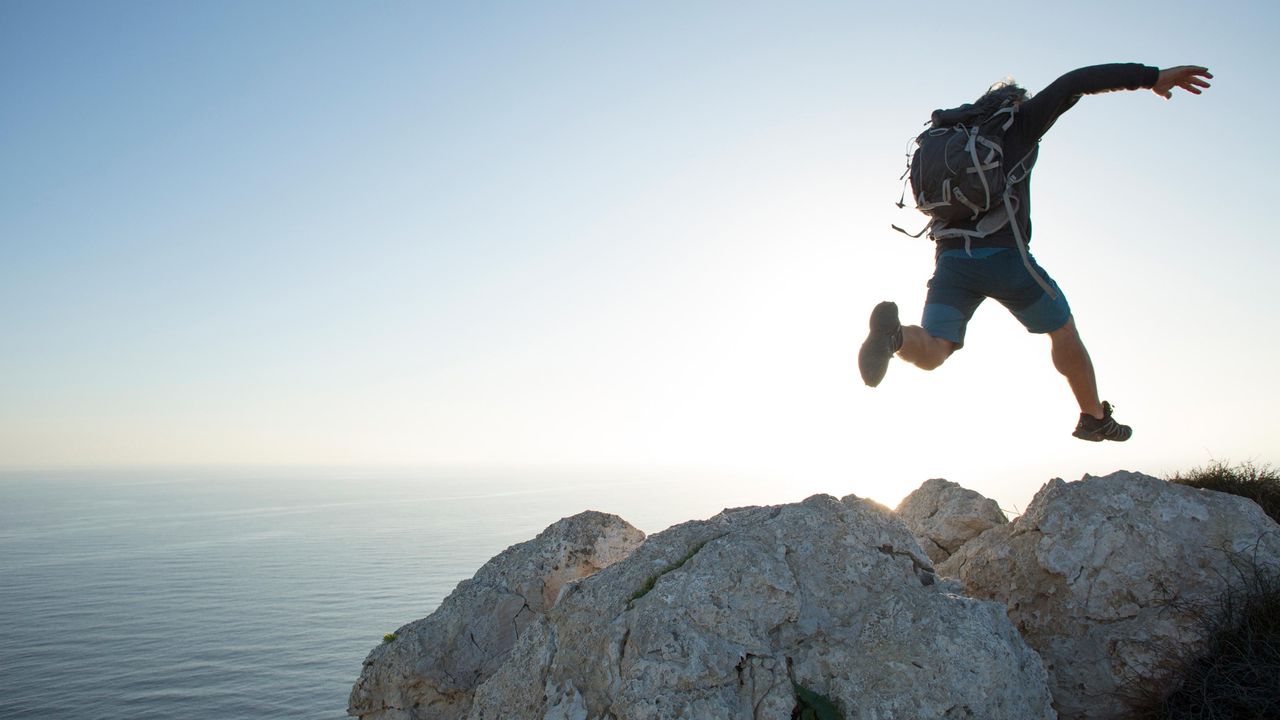 A hiker jumps from one rock to the next.